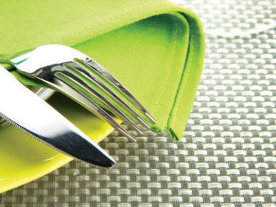 Close-up of cutlery and a woven placemat emphasizing texture, softness, and tactile surface quality