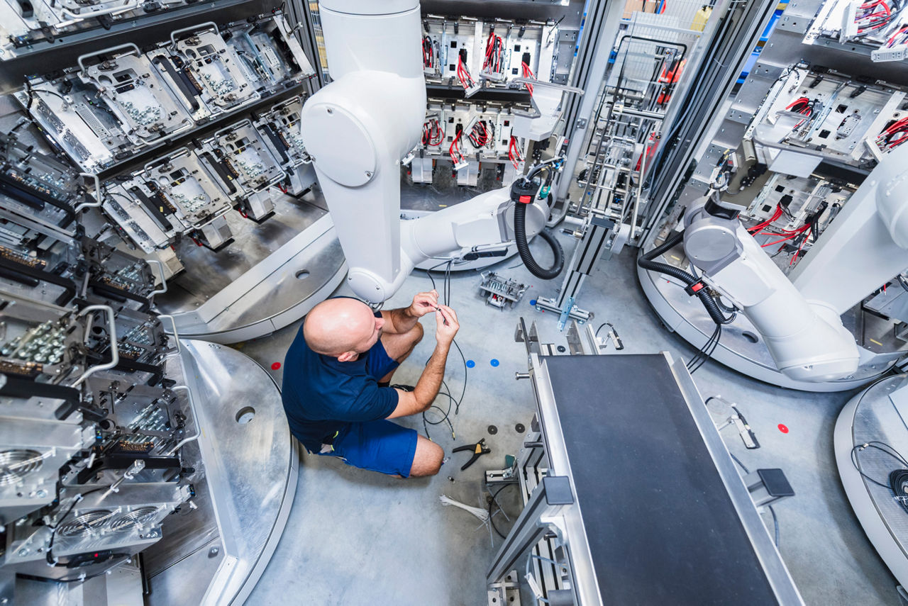 Technician repairing industrial robot in a production hall