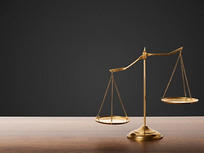 Gold brass balance scale on wooden table with black background