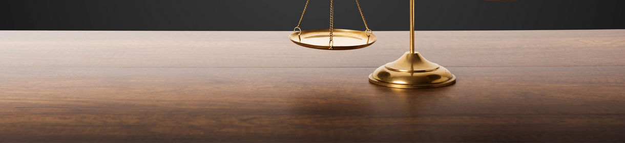 Gold brass balance scale on wooden table with black background