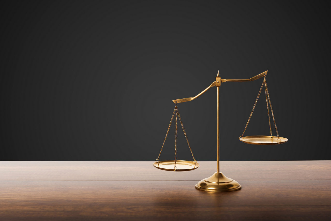 Gold brass balance scale on wooden table with black background