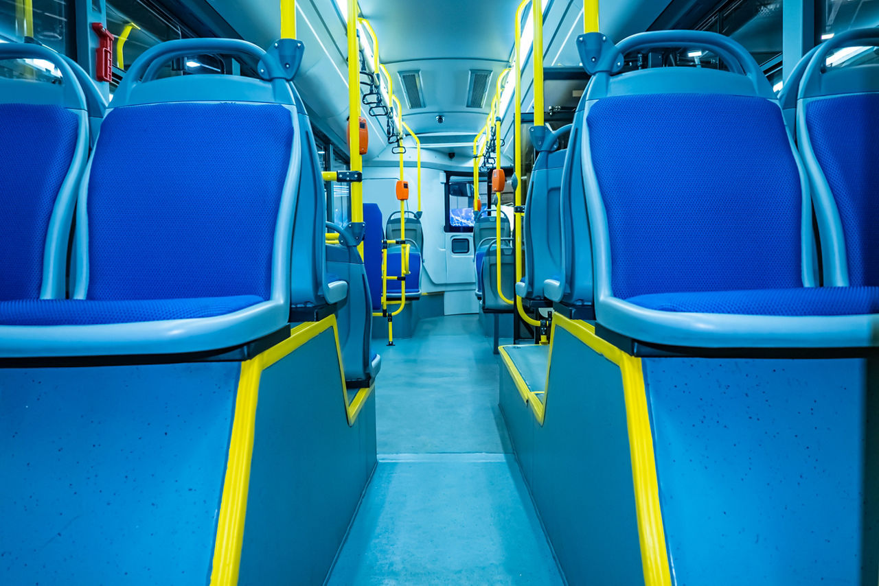 an image of a subway train with focus on seats and yellow handles