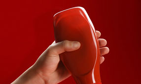 Tomato ketchup concept, a male hand squeezing ketchup bottle and the ketchup pouring in a bowl