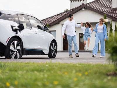Happy Family Enjoying Time Together Near Electric Car Outside Modern Home