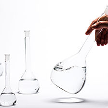 A hand testing chemical fluid in beaker jars