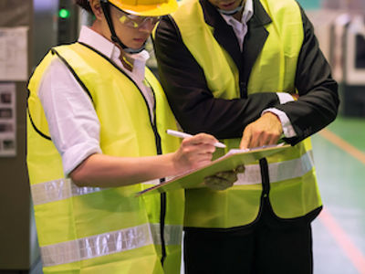 Spritzgusswerker in reflektierenden Westen bewerten Produktionsdokumentationen.