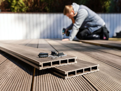 wpc terrace construction - worker installing wood plastic composite decking boards