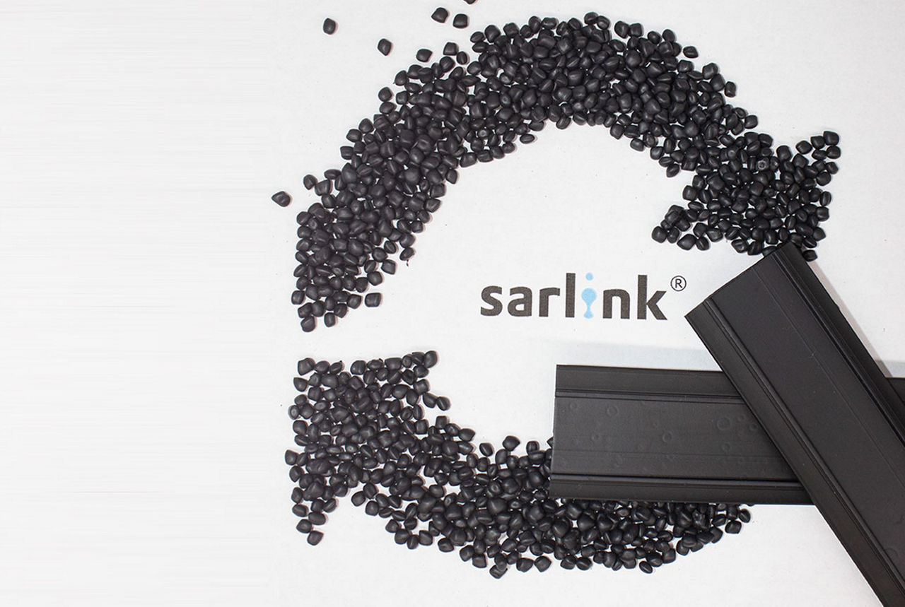 Black thermoplastic elastomer pellets laid in a circular economy icon shape with the sarlink logo in the middle