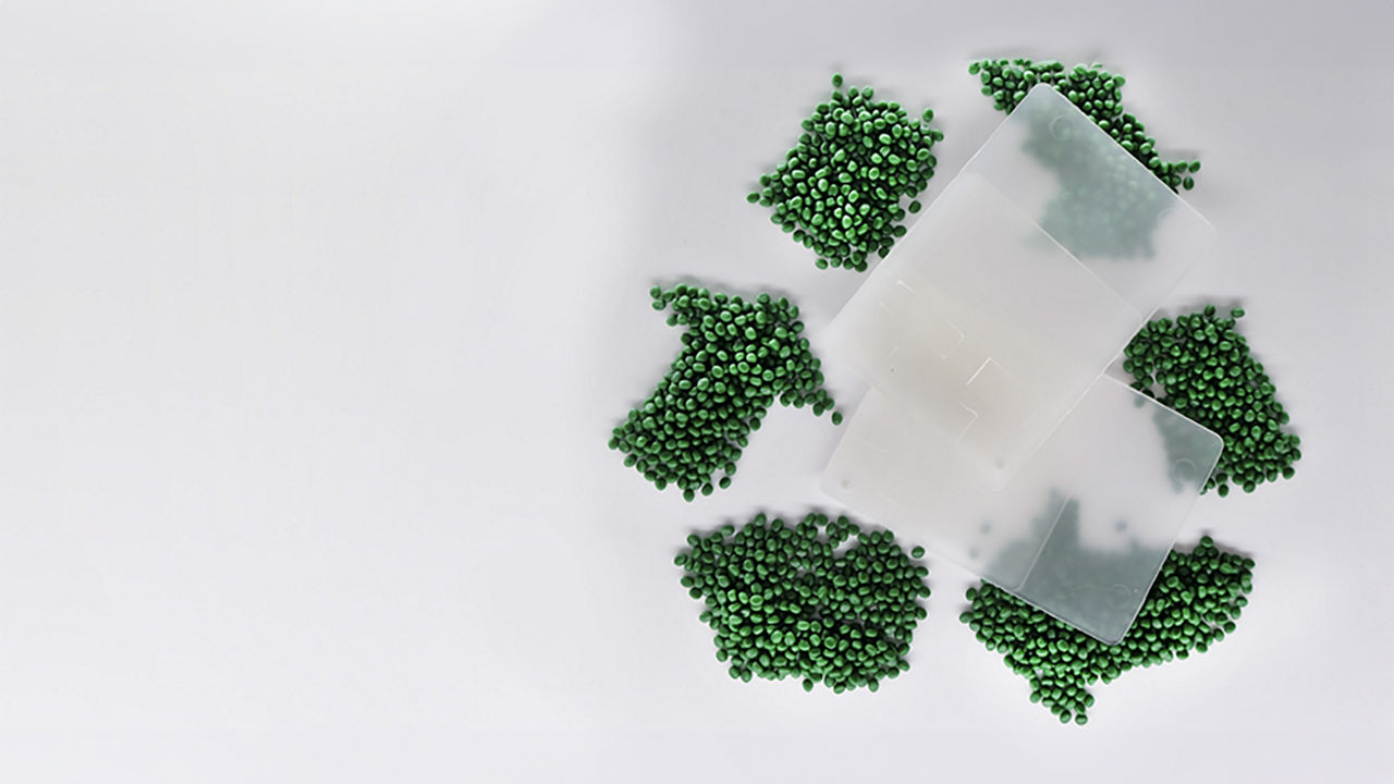 Green polymer pellets arranged in a recycling symbold