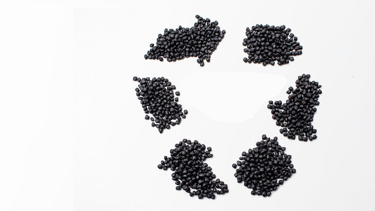 Black thermoplastic elastomer pellets laid in a circular economy icon shape