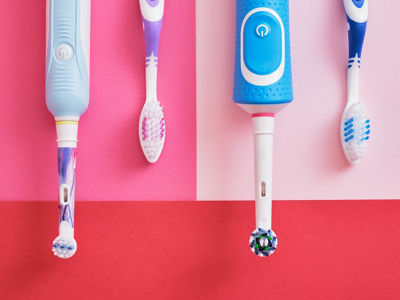 different toothbrushes on pink and red background, electric toothbrushes or plastic toothbrushes, environmental friendliness lifestyle concept, efficiency of brushing teeth