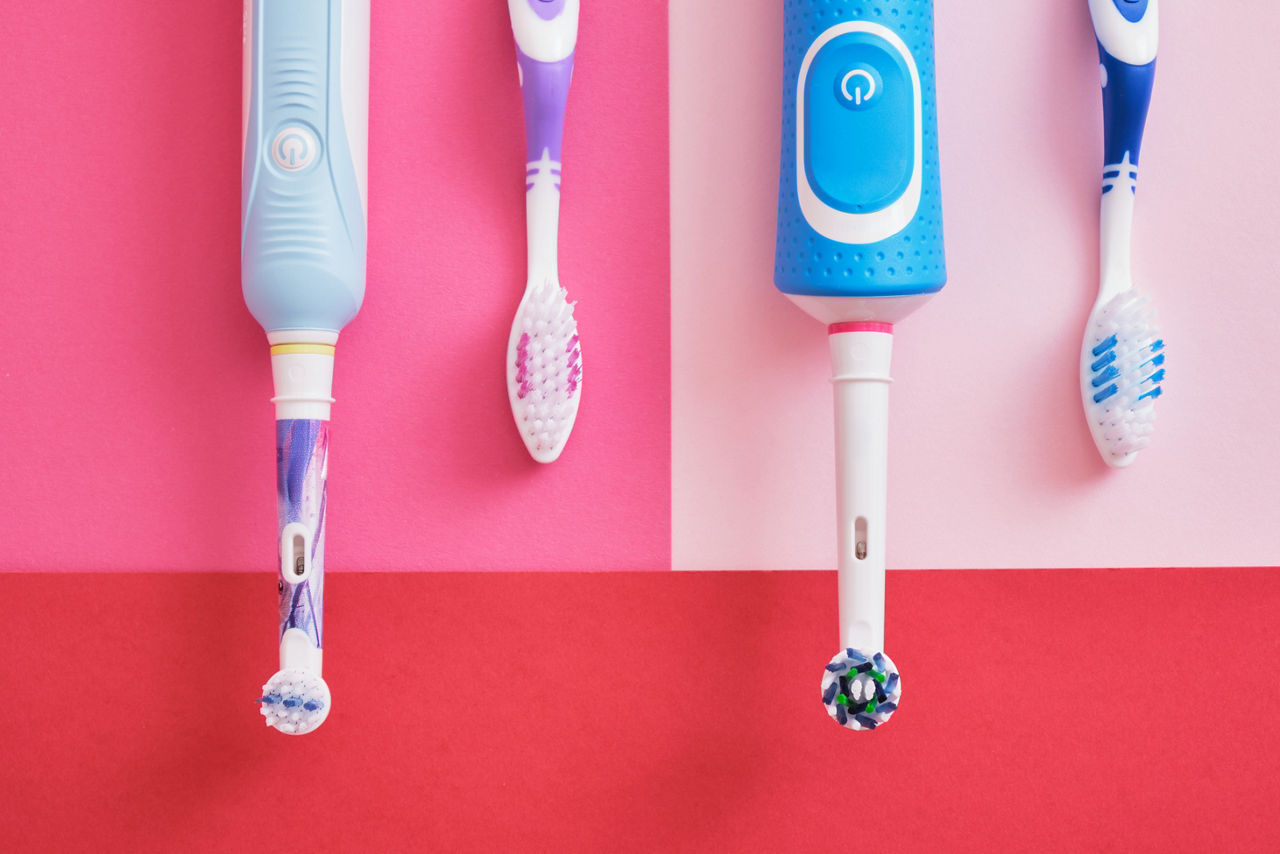 different toothbrushes on pink and red background, electric toothbrushes or plastic toothbrushes, environmental friendliness lifestyle concept, efficiency of brushing teeth