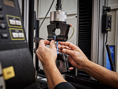 Hände testen die Dehnung eines TPE-extrudierten Materials in einem Labor