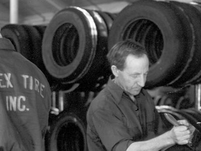Black and white photo of two men working in a tire shop