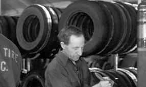 Black and white photo of two men working in a tire shop