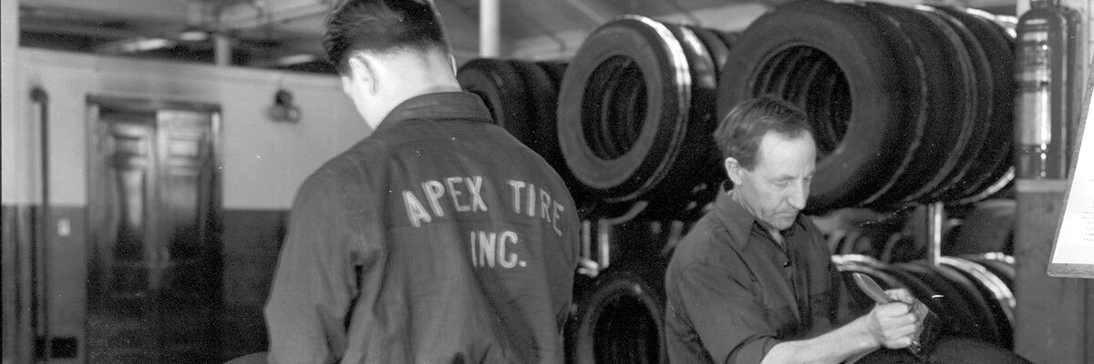 Black and white photo of two men working in a tire shop